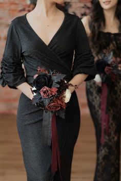 two women in black dresses are holding bouquets and one is wearing a dark colored dress