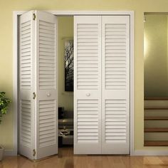 an open white door with shutters on the side and stairs to another room in the background