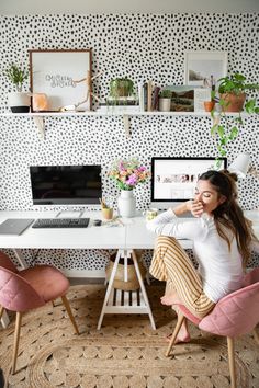 a woman sitting at a desk in front of a laptop computer on top of a white table