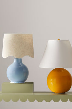 two lamps sitting on top of a shelf next to each other, one yellow and the other blue