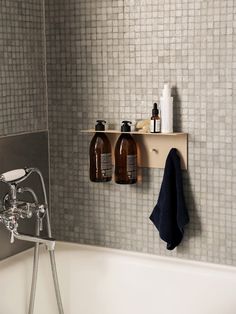 a bathtub with two bottles on the shelf above it