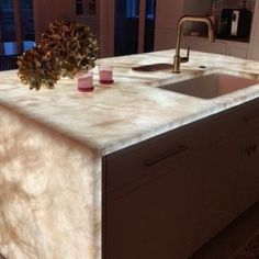 a kitchen counter with two cups on it and a sink in the middle, next to a window