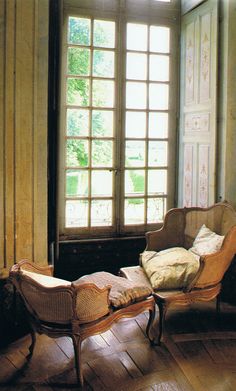 an old fashioned chair and ottoman in front of a window with sunlight streaming through it