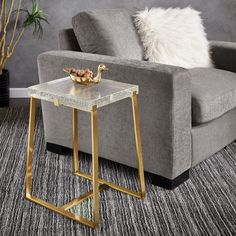 a living room with a couch, chair and side table in gold metal frame on carpeted flooring