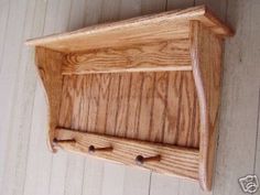 a wooden shelf with two hooks on the top and one door open to show it's contents