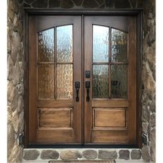 two double doors with glass on each side and stone wall behind them, in front of a brick building