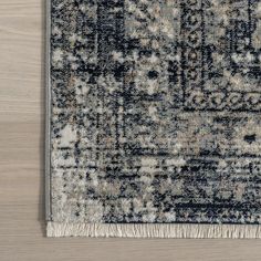 an area rug with fringes on top of it and a wooden floor in the background