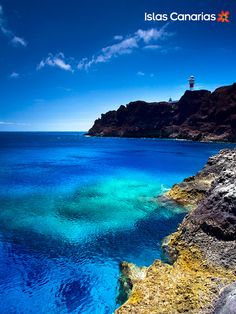 the water is crystal blue and clear at this point in the ocean with a light house on top