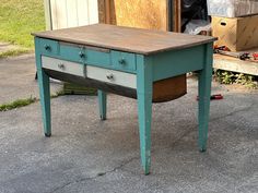 an old blue table with drawers on it