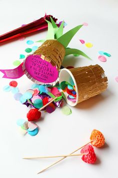 an ice cream cone and candy on a white surface with confetti scattered around it
