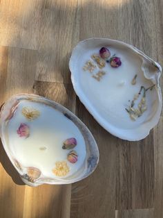 two empty dishes with flowers on them sitting on a wooden table next to each other