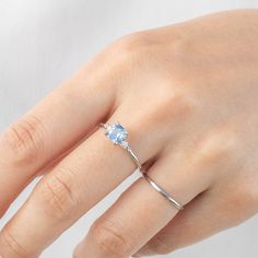 One of a kind, the ring in the photo is what you will receive 0.91ct Montana Sapphire, 5.5x5.5x3.37mm, heat treated, a white feather inclusion near the edge 0.04ctw G color SI clarity white accent diamonds Band width x height: approx. 1.4mm x 1.6mm Hight profile, four-prong flower setting Made of 100% recycled solid 14k white gold and ethically sourced gemstones Ring Size This ring is currently size 7, and can be resized 3~8.5 in 10 days. For other ring size, it is going to be a semi-custom orde Rose Gold Sapphire Diamond Ring With Round Cut, Dainty White Gold Crystal Ring With Prong Setting, Diamond Solitaire Open Birthstone Ring, Solitaire Diamond Open Ring Birthstone, Diamond Solitaire Birthstone Ring With Open Design, Diamond Solitaire Birthstone Ring With Open Ring Shape, Solitaire Ring For Proposal In Fine Jewelry Style, Minimalist Brilliant Cut Ring For Proposal, Diamond Moonstone Promise Ring