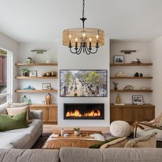 a living room filled with furniture and a fire place under a chandelier hanging from the ceiling