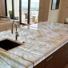 a kitchen counter top with a sink in the middle and an open living room to the side