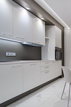 a modern kitchen with white cabinets and marble flooring, along with a dining room table set for four