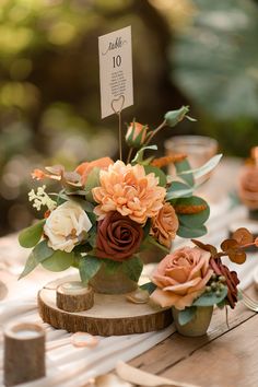 an arrangement of flowers on a table with place cards and napkins in the background