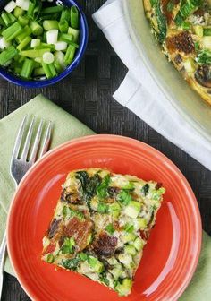 a slice of vegetable quiche on an orange plate next to a bowl of green vegetables