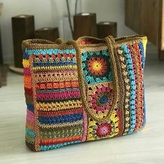 a multicolored crocheted bag sitting on top of a wooden table next to a vase