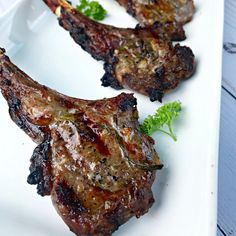 three pieces of meat sitting on top of a white plate next to a green leafy garnish