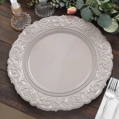 a white plate sitting on top of a wooden table next to silverware and flowers