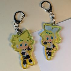 two keychains with cartoon characters on them sitting on a table next to each other