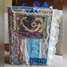 an altered book is sitting on a chair with laces and fabric around the edges