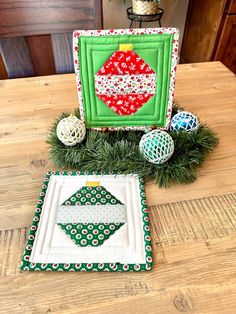 two quilted christmas ornaments sitting on top of a wooden table