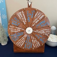 a wooden spinning wheel with the names of different languages on it next to a bowl of marshmallows