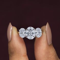 a woman's hand holding a three stone diamond ring