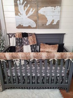 a baby crib in front of two paintings on the wall and a christmas tree