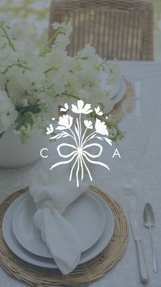 the table is set with white flowers and place settings