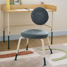 a chair sitting in front of a desk with a computer on it and a rug