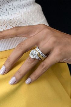 a woman's hand with two rings on top of her ring and yellow dress