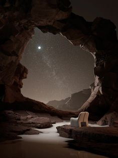 a chair sitting on top of a rocky beach under a sky filled with stars