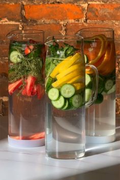 three pitchers filled with different types of fruits and vegetables