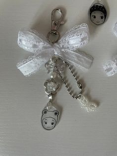 three key chains with charms attached to them on a white surface, one has an animal face and the other has a bow