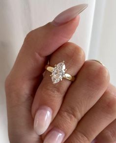 a woman's hand holding an engagement ring with a diamond on the middle finger