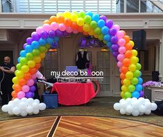 an arch made out of balloons on top of a wooden floor in front of a building