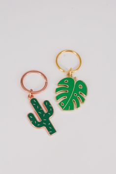 two green and gold keychains one with a cactus, the other with a leaf