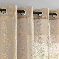 a curtain with gold speckles hanging from it's black metal rod ends