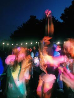 blurry image of people dancing at night in the park with bright lights on them