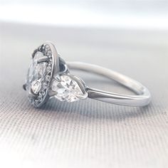 an engagement ring with two pear shaped diamonds on it's side, set in white gold