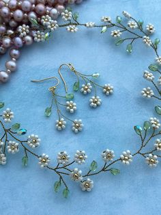 pearls and green glass beads are arranged on a blue surface with other jewelry items in the background