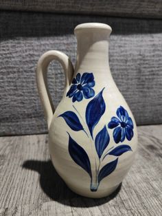 a blue and white flowered vase sitting on a wooden table next to a couch