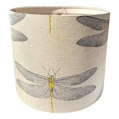 a lampshade with dragonflies on it's back and yellow thread in the middle