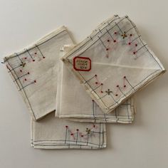 four napkins with embroidered designs on them