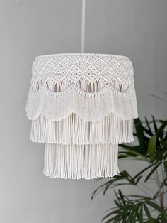 a white chandelier with fringes hanging from it's ceiling next to a potted plant