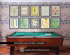 a pool table in front of a brick wall with eight framed games on the wall