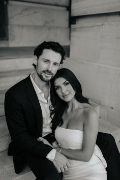 a man and woman sitting next to each other on the steps in front of a building