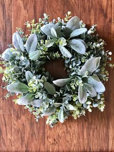 a wreath is hanging on the wall next to a wooden door with green leaves and buds